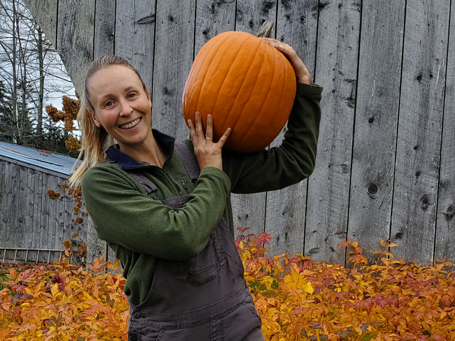 Hannah holds a pumpkin up, smiling