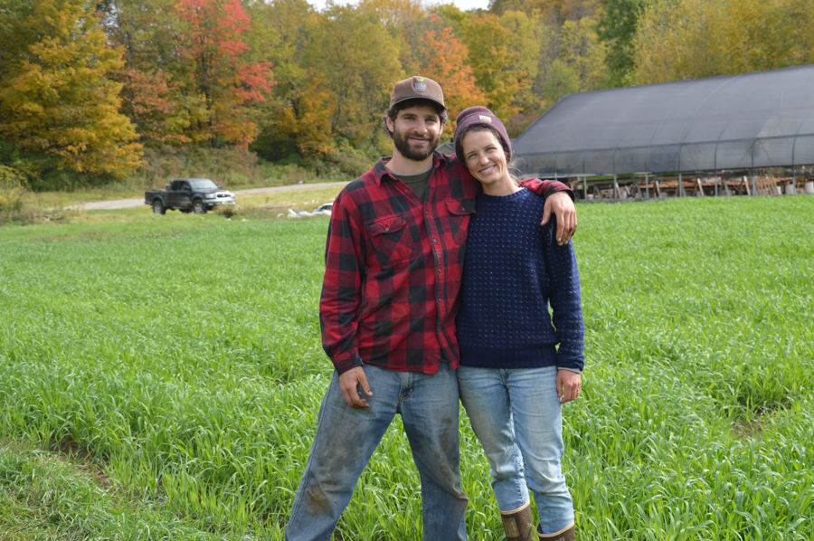 Two farmers smile in a field