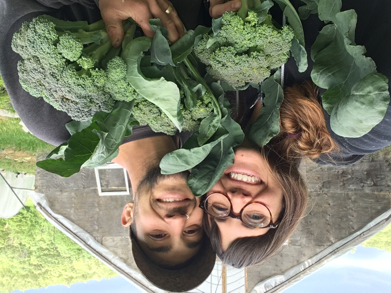 Two people hold veggies up, smiling