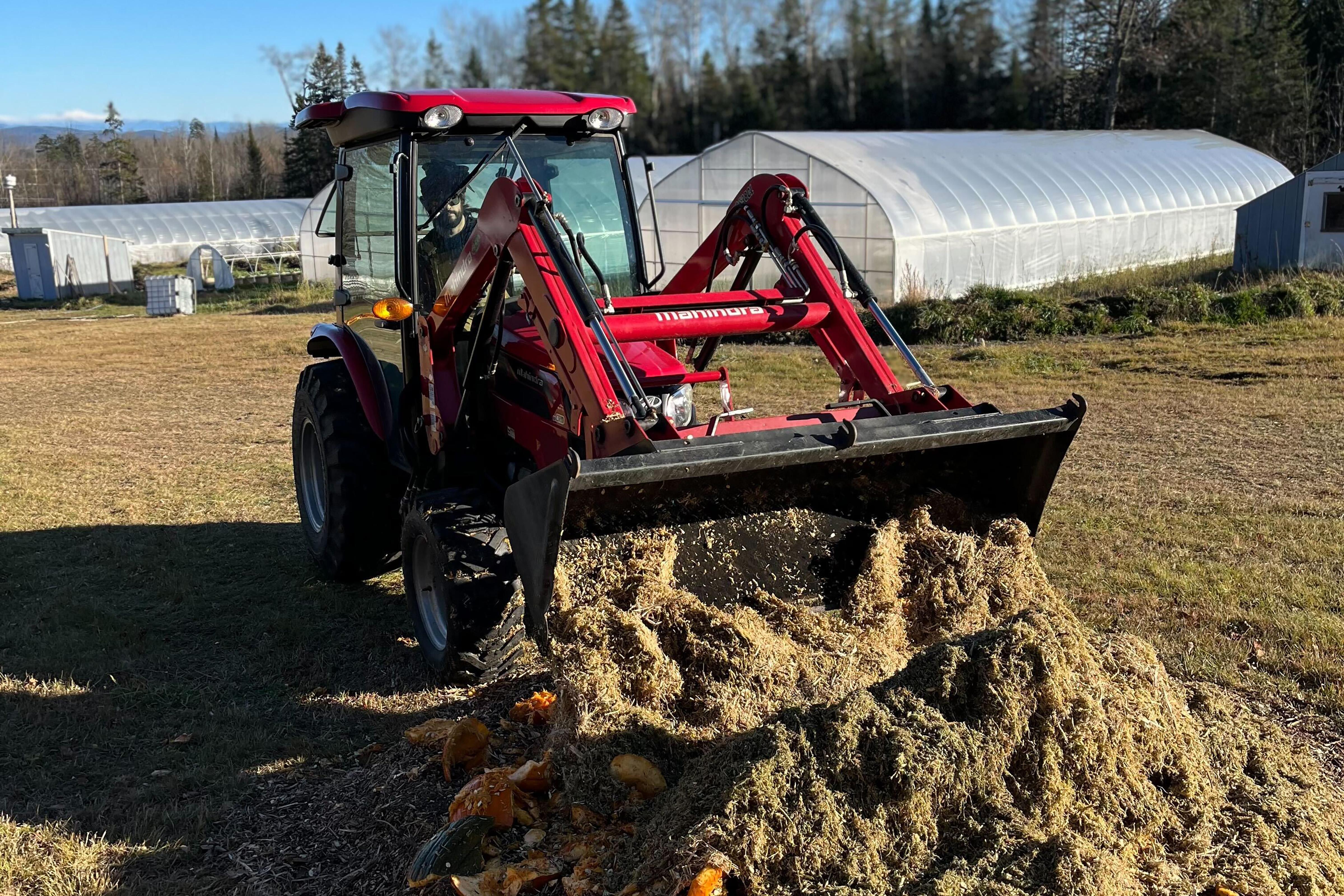 A red tractor moves a pile of Johnson Su compost