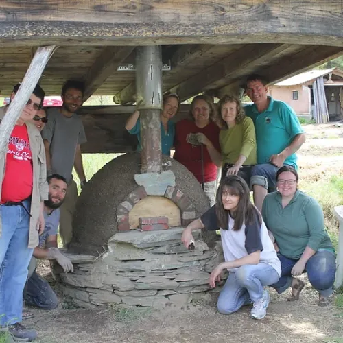 Workshop participants gathered around their constructed Cob Pizza Oven.