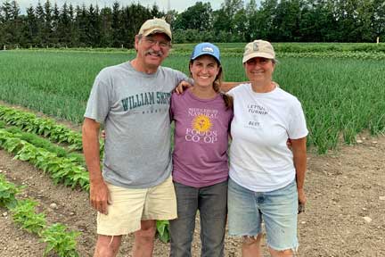 Will, Pauline, & Judy Stevens of Golden Russet Farm with their fields in the background