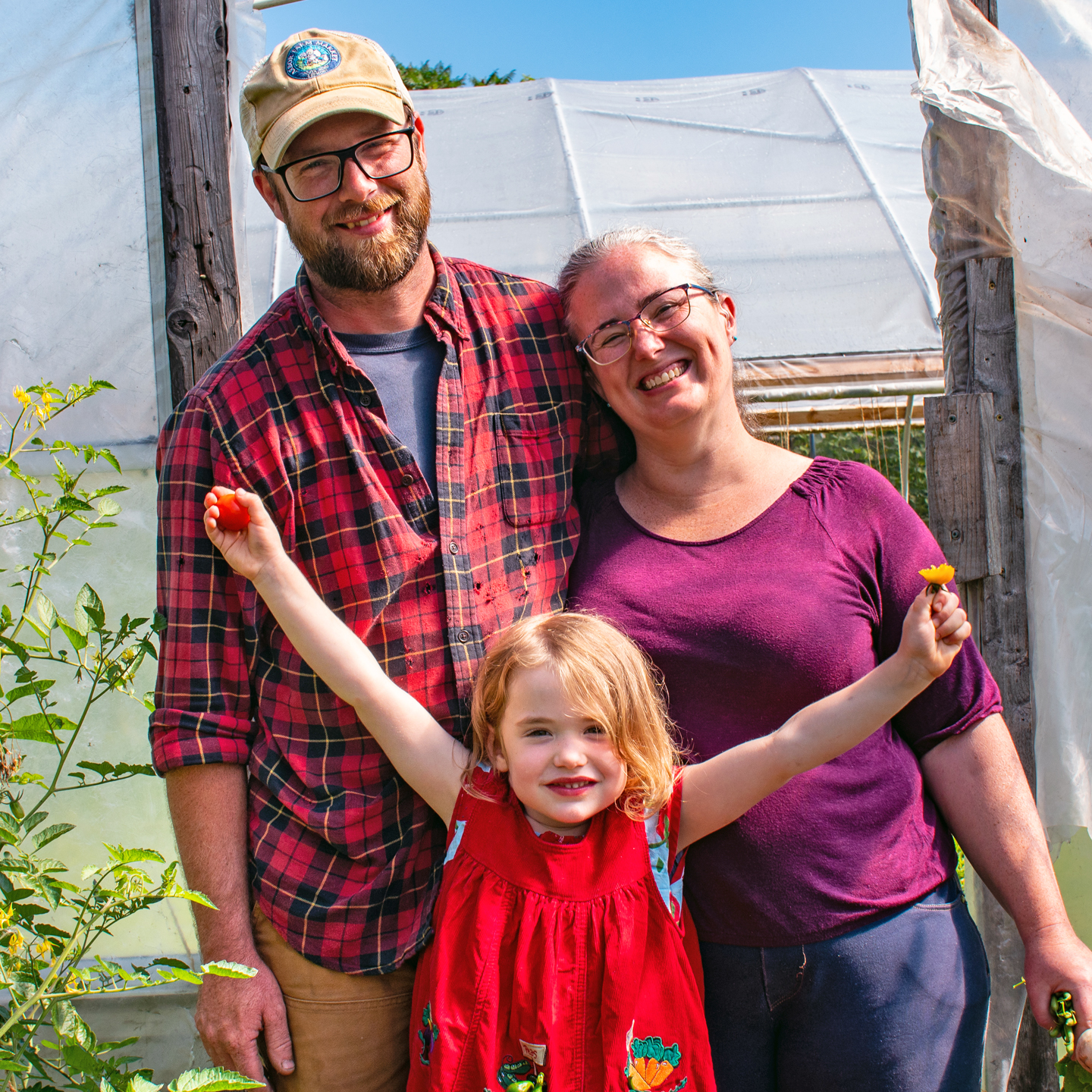 Patrick Helman of Sandy Bottom Farm poses in front of a high tunnel with his family