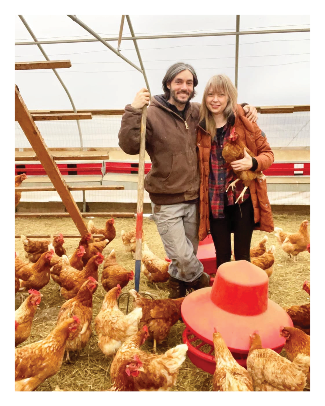 Two people stand amongst chickens