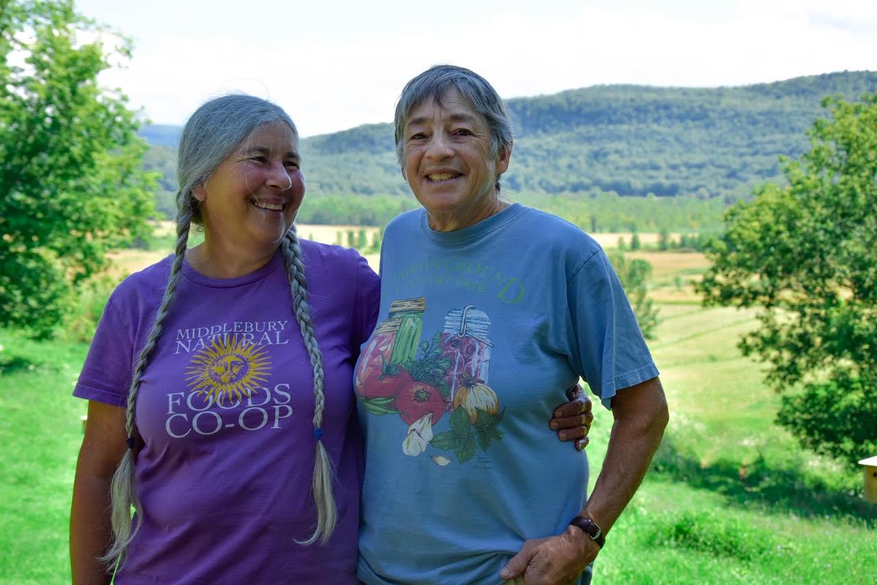 Two farmers stand smiling in a field.