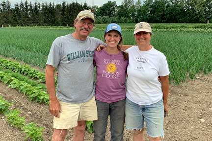 Will, Pauline, and Judy Stevens of Golden Russet Farm with their farm fields in the background