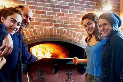 Bakers surround the wood-fired oven at Naga Bakehouse