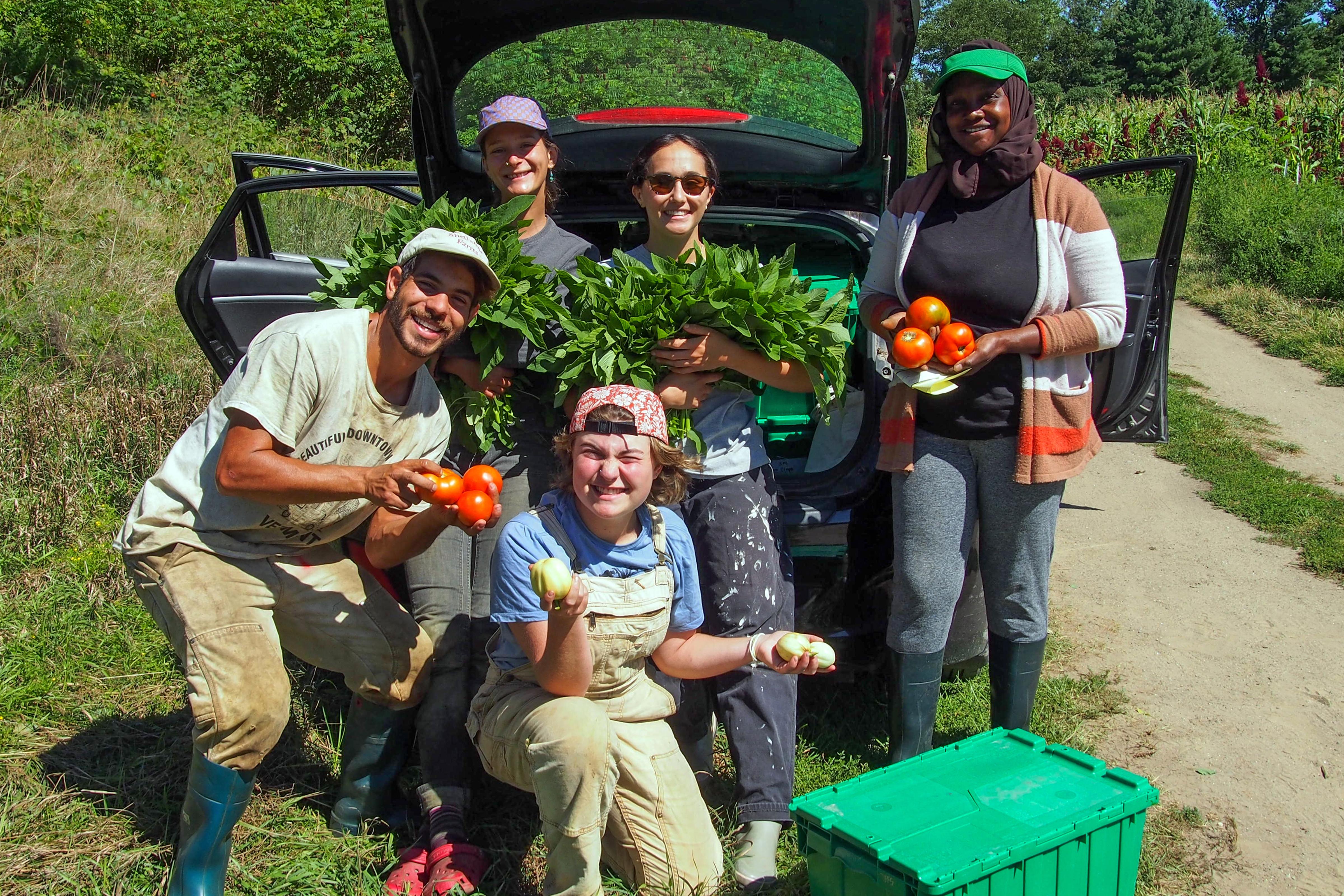 Smiling faces with hands full of produce at the People's Farmstand