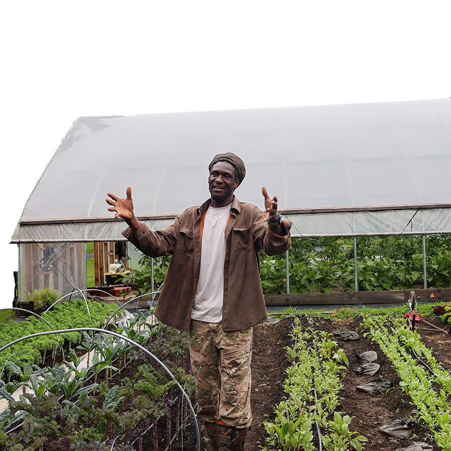 A farmer stands in a small crop bed, talking.