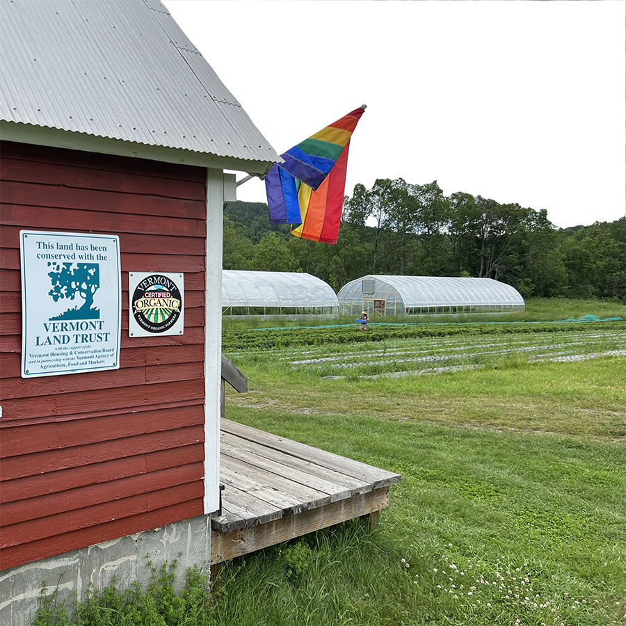 A barn in front of crop fields with a Vermont Organic Farmers sign