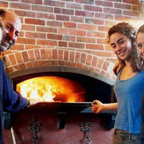 Bakers surround the wood-fired oven at Naga Bakehouse