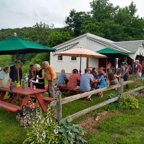 People eating at picnic tables outdoors on a farm