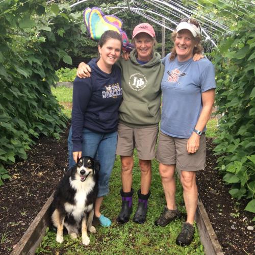 three people and dog surrounded by bean vines